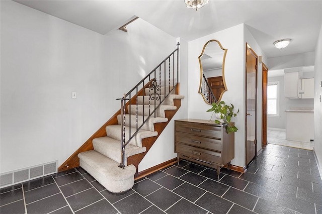 stairs featuring visible vents, baseboards, and stone tile floors