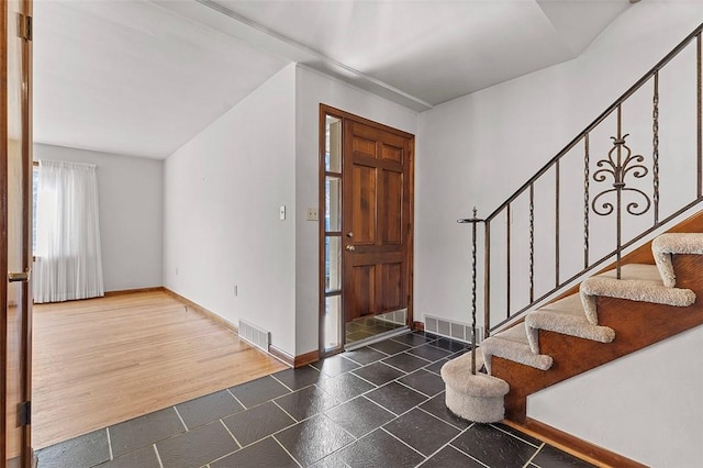 foyer entrance with wood finished floors, stairway, baseboards, and visible vents