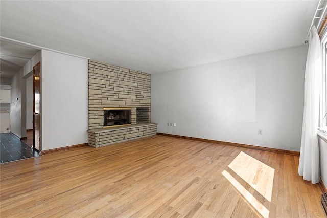 unfurnished living room featuring wood finished floors, a fireplace, and baseboards