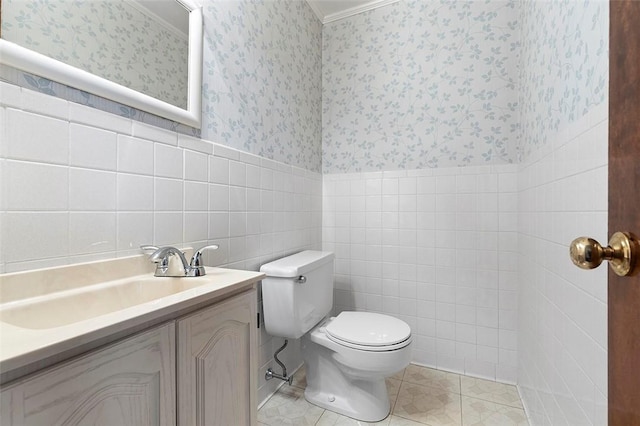 half bath with a wainscoted wall, vanity, and wallpapered walls