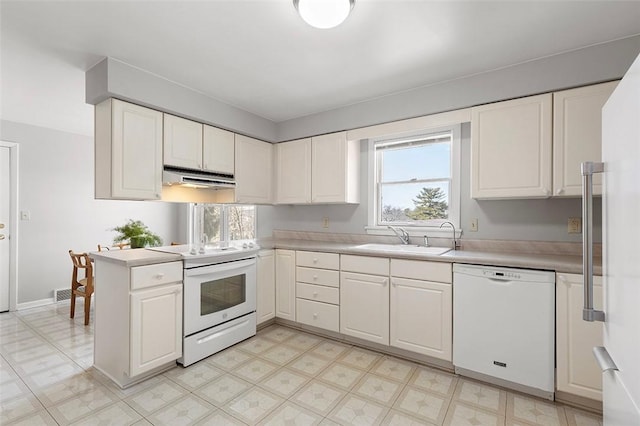 kitchen featuring under cabinet range hood, white appliances, light countertops, and a sink