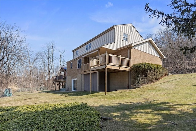 rear view of house with a yard, fence, brick siding, and a wooden deck