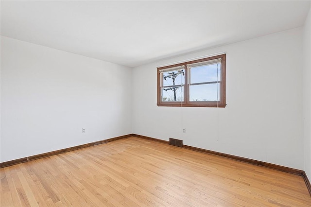 spare room with visible vents, baseboards, and light wood finished floors