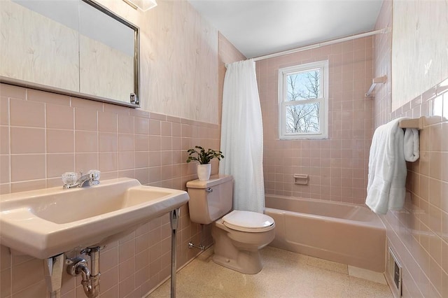 bathroom featuring visible vents, toilet, wainscoting, shower / tub combo, and tile walls