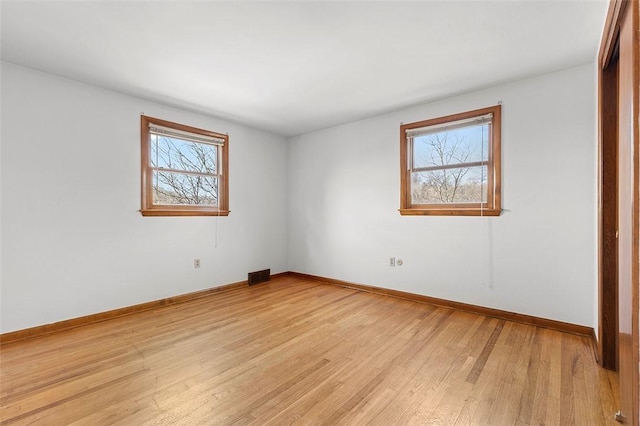 unfurnished bedroom with visible vents, multiple windows, light wood-style floors, and baseboards