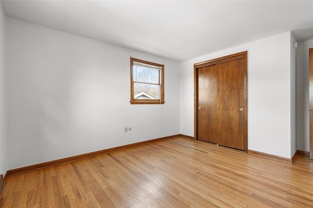 unfurnished bedroom with a closet, baseboards, and light wood-style flooring