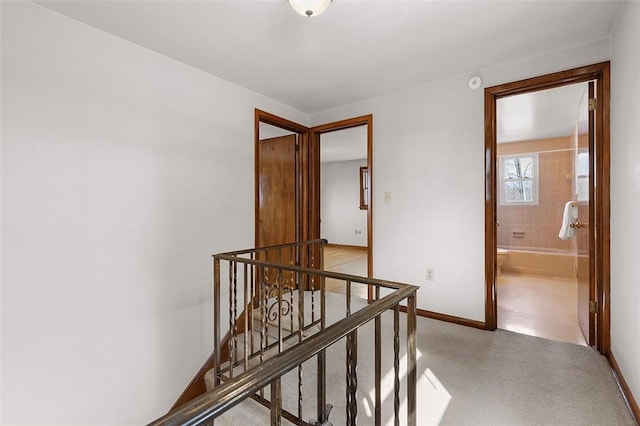 hall featuring baseboards and an upstairs landing