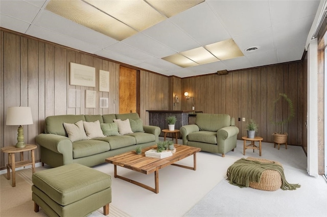 living room featuring visible vents, light colored carpet, and wood walls