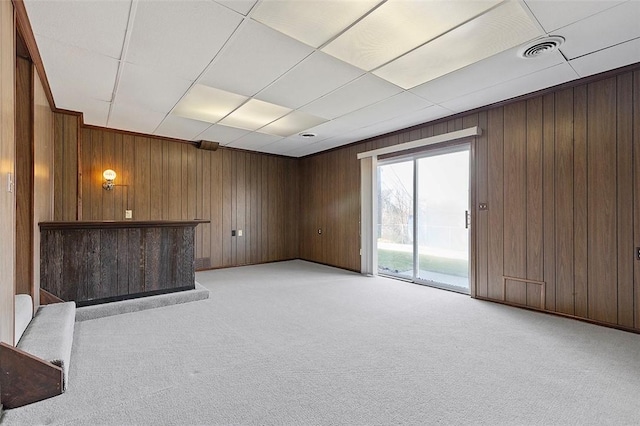 unfurnished living room featuring light colored carpet, visible vents, and wood walls