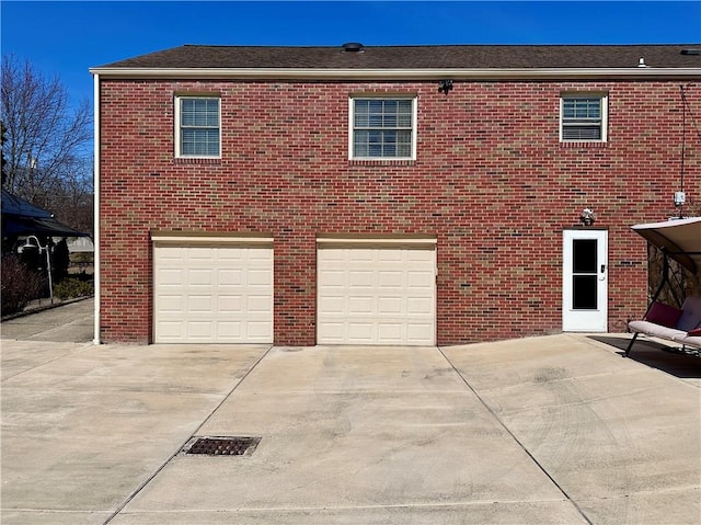 exterior space featuring an attached garage, brick siding, and driveway