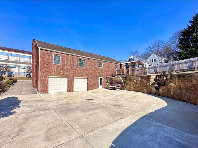 back of house featuring brick siding, an attached garage, and driveway