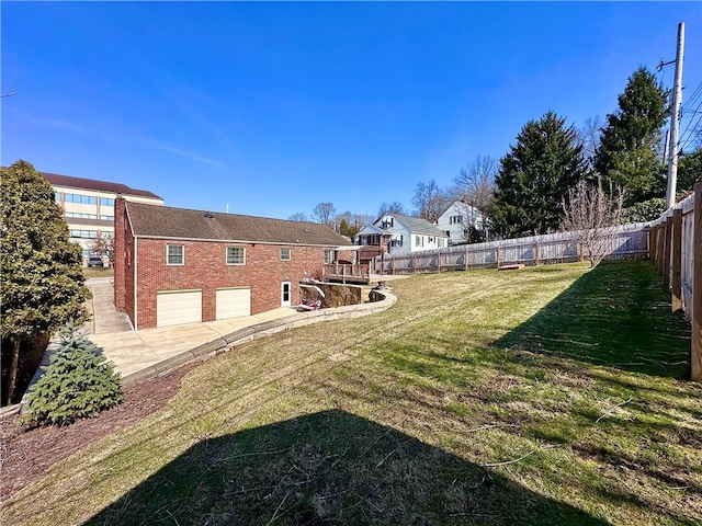 view of yard featuring driveway, fence private yard, and a garage