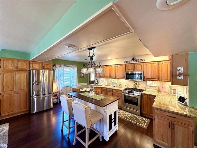 kitchen featuring dark wood finished floors, decorative backsplash, stainless steel appliances, and light stone countertops