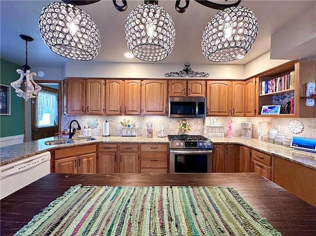 kitchen with backsplash, light stone counters, an inviting chandelier, stainless steel appliances, and a sink