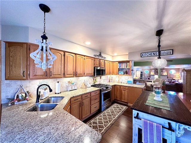 kitchen featuring a sink, light stone counters, dark wood-style floors, appliances with stainless steel finishes, and decorative backsplash