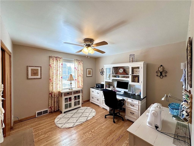 home office with visible vents, baseboards, light wood-style flooring, and a ceiling fan