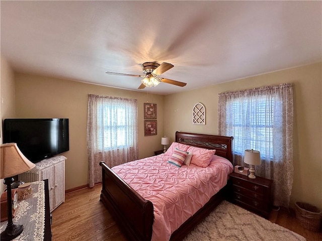 bedroom featuring baseboards, wood finished floors, and a ceiling fan