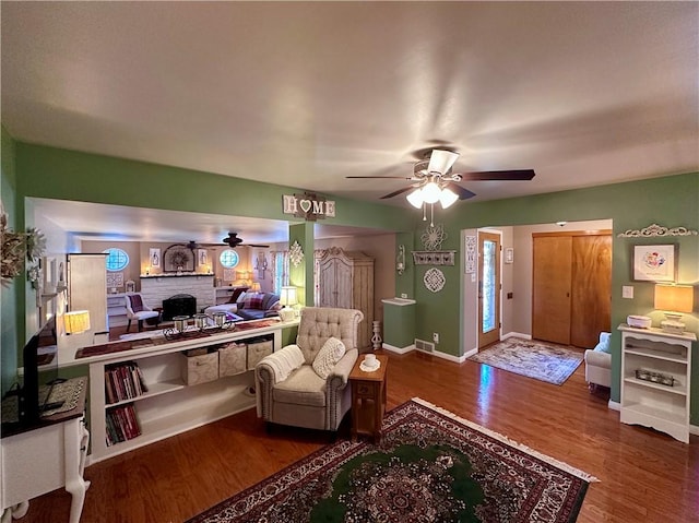 living room with visible vents, baseboards, wood finished floors, and a ceiling fan