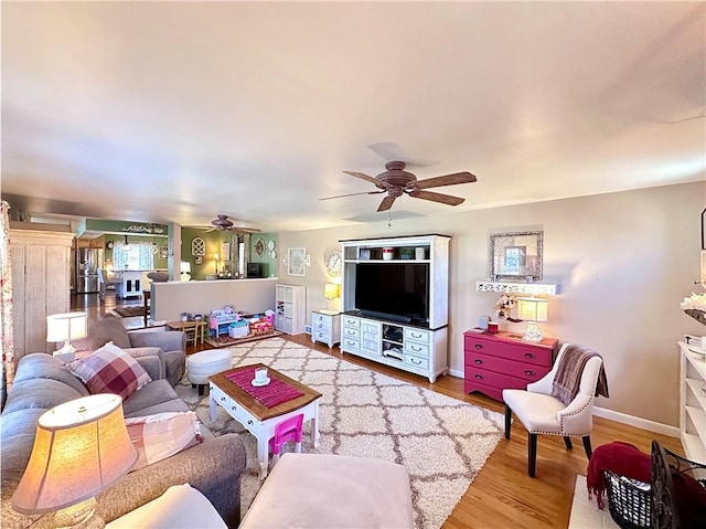 living room with baseboards, ceiling fan, and wood finished floors