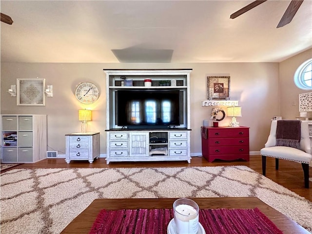 living area featuring wood finished floors, baseboards, and ceiling fan