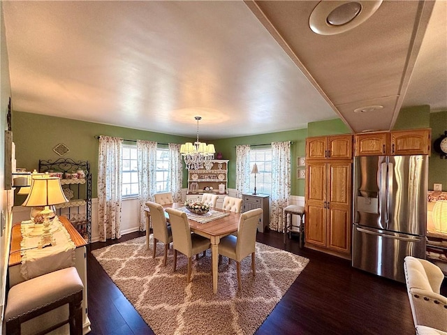 dining area with a wealth of natural light, a notable chandelier, and dark wood finished floors