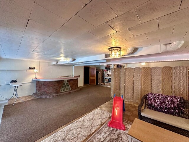 finished basement featuring visible vents, carpet floors, a bar, and concrete block wall