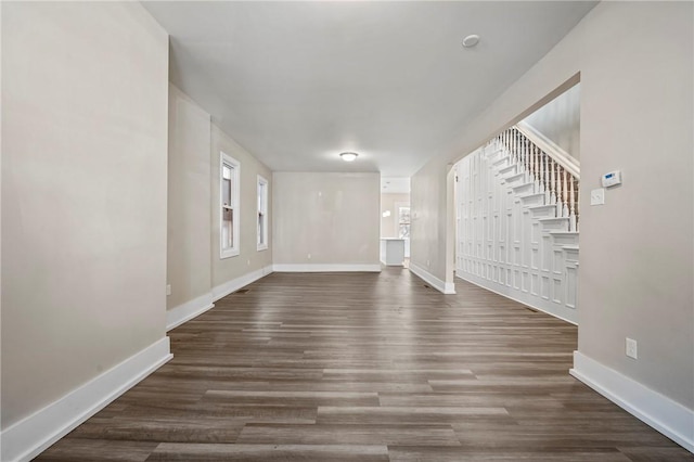 unfurnished living room with stairway, baseboards, and wood finished floors