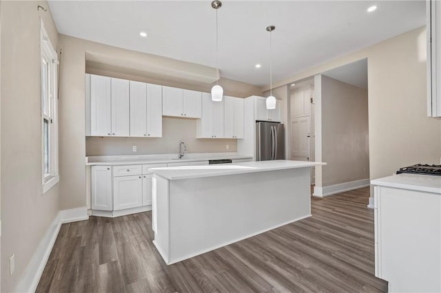 kitchen with dark wood-type flooring, a sink, freestanding refrigerator, white cabinets, and light countertops