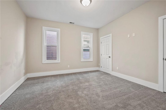 carpeted empty room featuring visible vents and baseboards