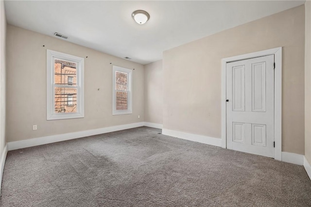 carpeted empty room with visible vents and baseboards