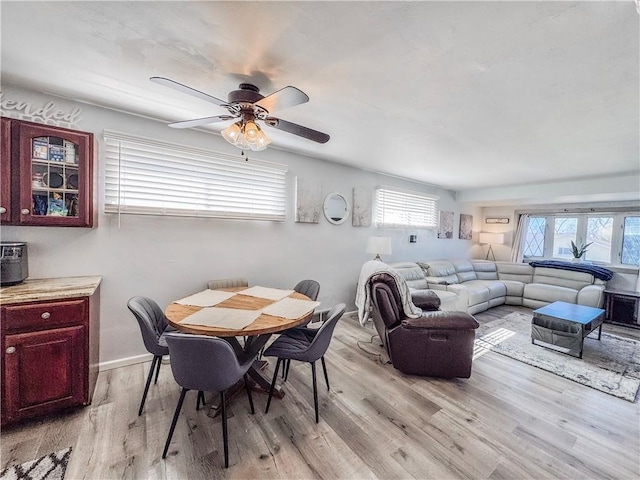 dining space with baseboards, ceiling fan, and light wood finished floors