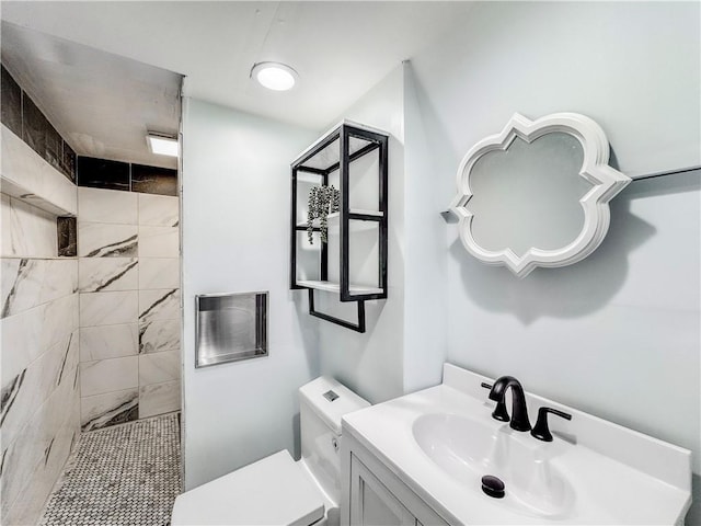 bathroom with tiled shower, toilet, and vanity