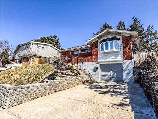 view of front of house with brick siding, an attached garage, fence, stairway, and driveway