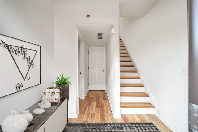 stairs with wood finished floors, visible vents, and baseboards