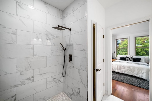 bathroom featuring a tile shower, ensuite bath, and wood finished floors