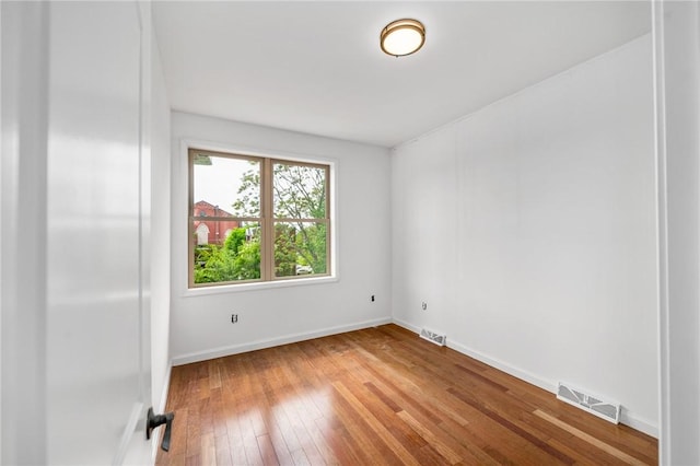 spare room with visible vents, baseboards, and hardwood / wood-style flooring