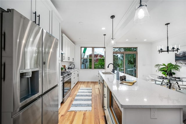 kitchen with a sink, white cabinetry, appliances with stainless steel finishes, crown molding, and a large island with sink