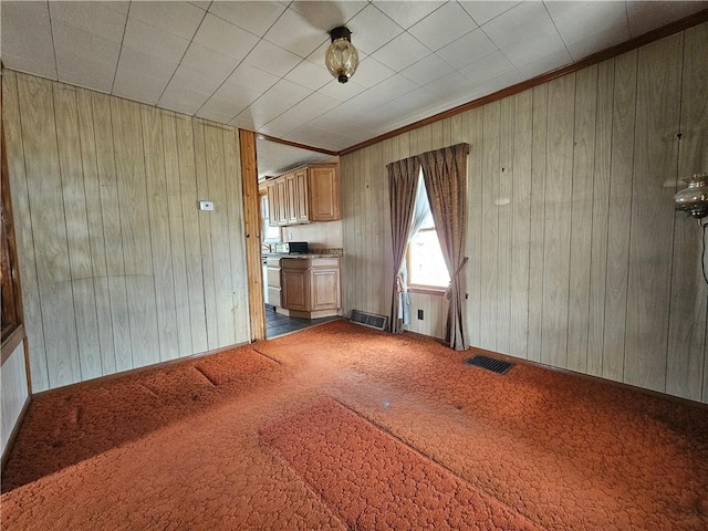 unfurnished living room with visible vents, carpet floors, and wooden walls