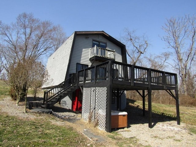 view of home's exterior featuring a deck, a balcony, stairway, and a gambrel roof