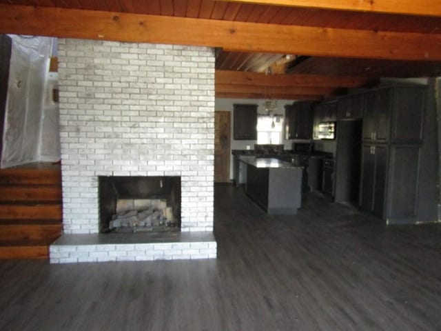 unfurnished living room with dark wood finished floors, beamed ceiling, a fireplace, and wood ceiling