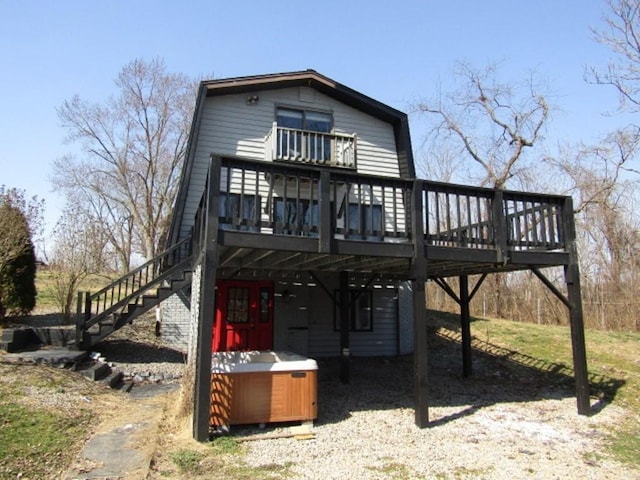 back of property featuring stairs, a deck, and a hot tub