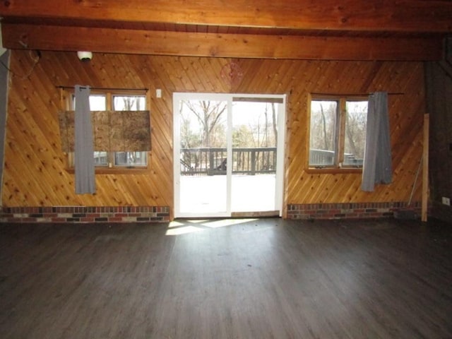 empty room featuring beamed ceiling, wood walls, and wood finished floors