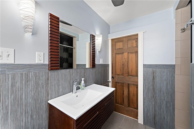 bathroom with tile patterned flooring, a wainscoted wall, vanity, and tile walls