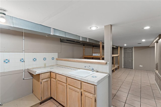 kitchen with a sink, tasteful backsplash, tile countertops, and light tile patterned floors