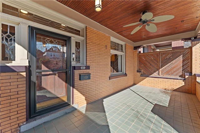 doorway to property featuring brick siding and a ceiling fan