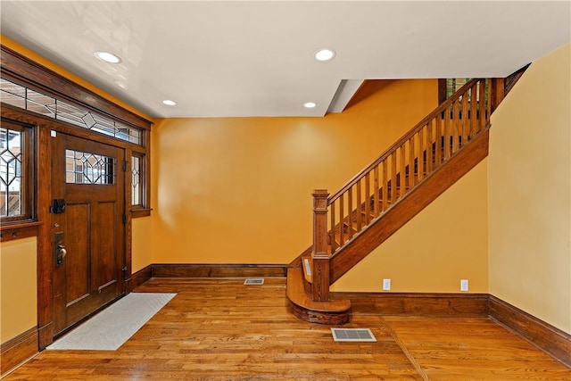 entryway with hardwood / wood-style floors, recessed lighting, baseboards, and visible vents