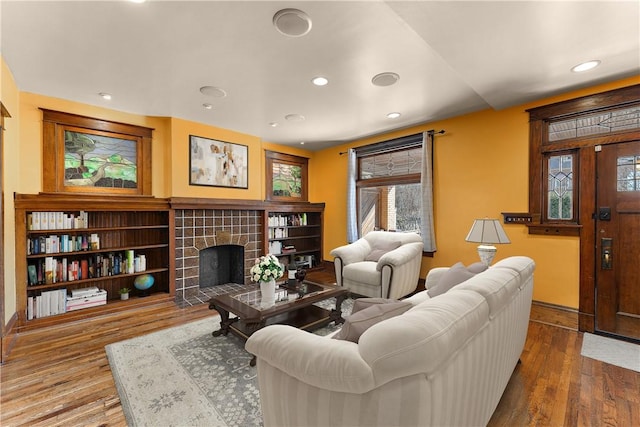 living room with a tiled fireplace, recessed lighting, wood finished floors, and baseboards