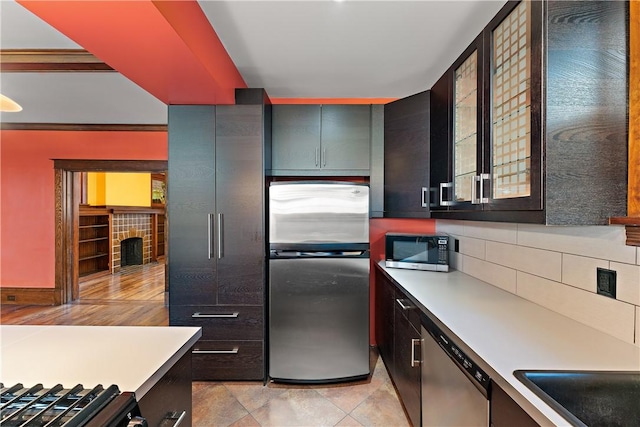 kitchen with light countertops, glass insert cabinets, tasteful backsplash, and appliances with stainless steel finishes