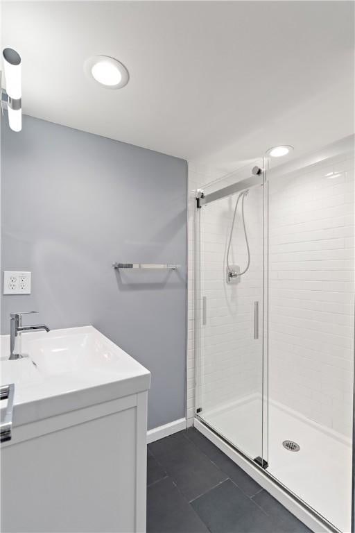 full bath featuring vanity, baseboards, a stall shower, and tile patterned flooring