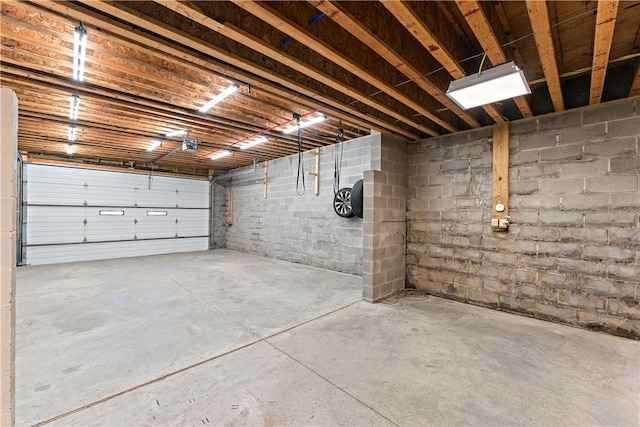 garage featuring concrete block wall and a garage door opener